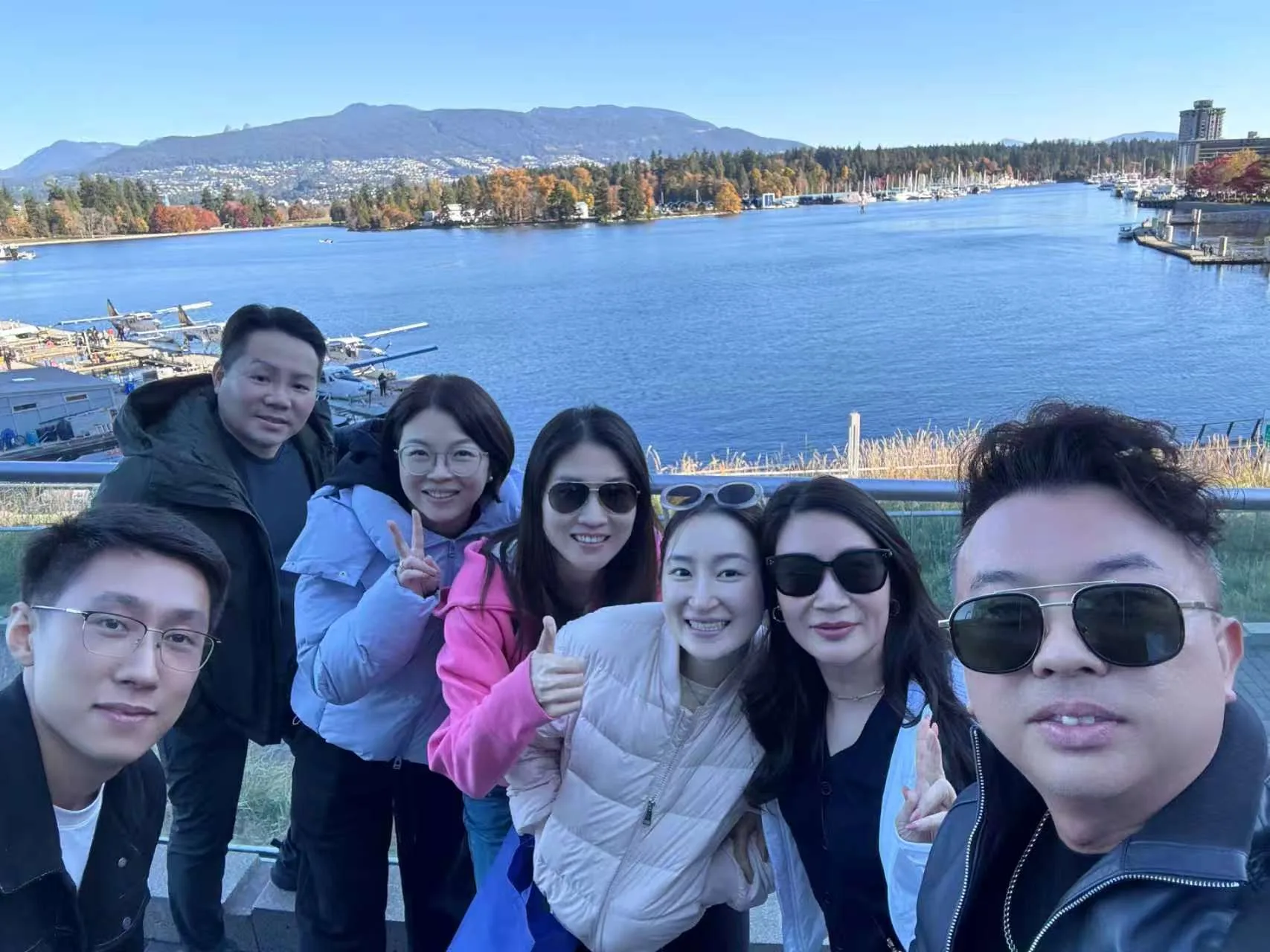 Seven Guaranti Mortgage team members take a waterfront group photo with the water and mountains behind them