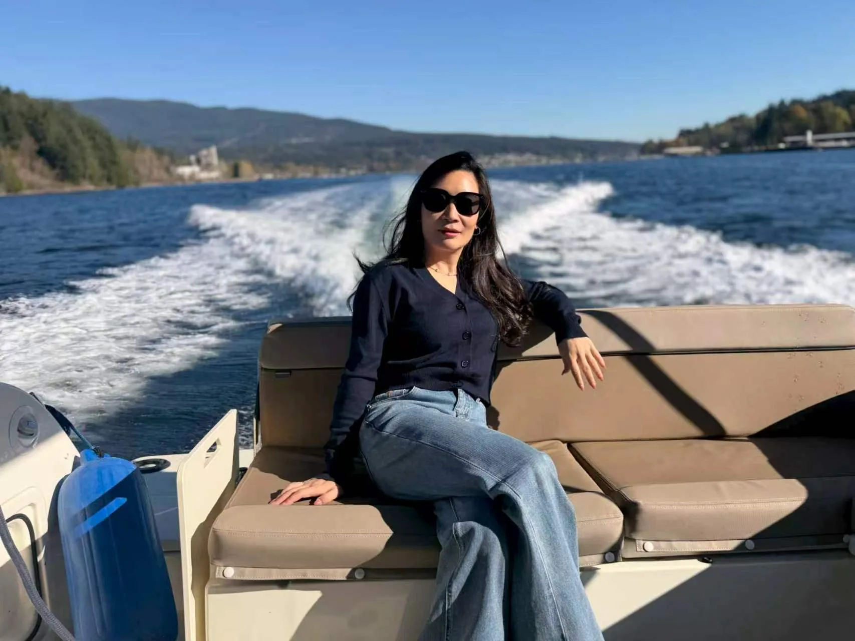 A team member relaxes on the boat with the water and boat wake behind her